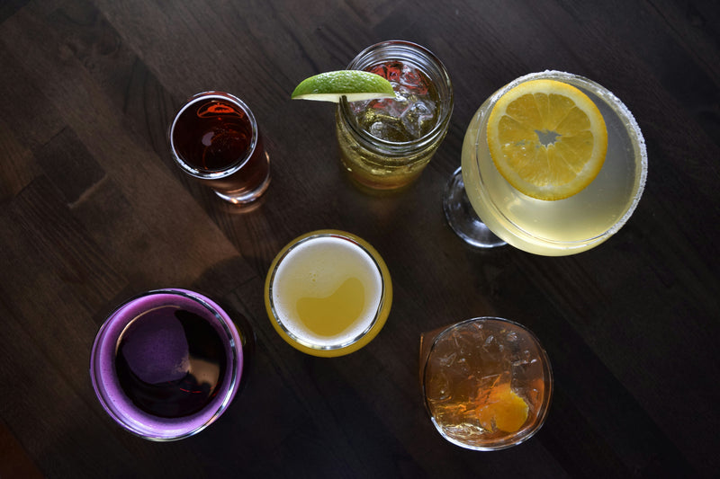 Assorted terpene and CBD-inspired drinks on a wooden table with citrus garnishes
