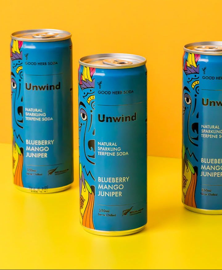 Three cans of 'Unwind' soda with colorful designs on a yellow background